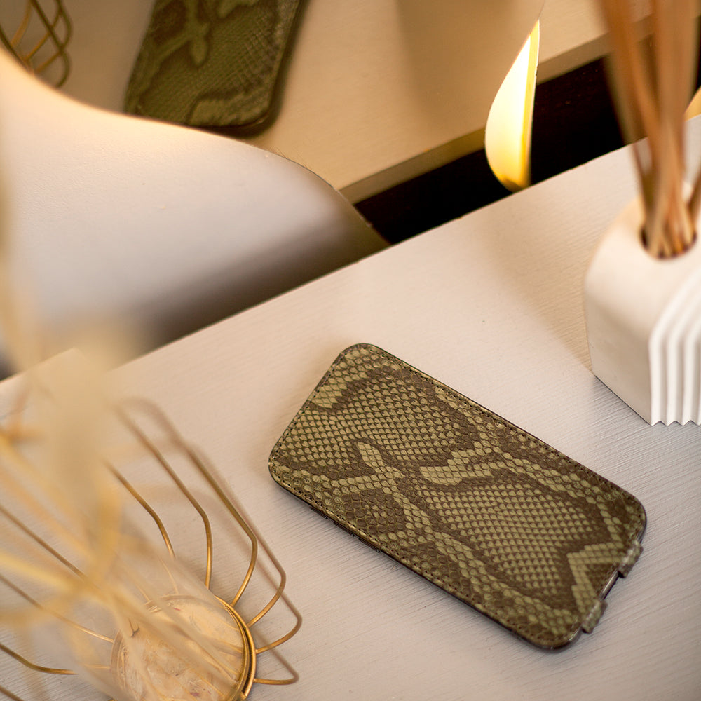Phone in python leather case on a table with decorative items